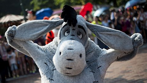 Eeyore at a Disney theme park, stretching out his ears and posing