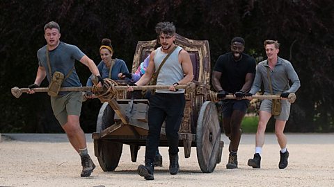 An image showing players from The Traitors pushing a single seat carriage as part of a mission