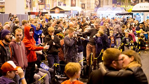 Mannequin Challenge at Comic Con Birmingham, 2016. A crowd of people stand frozen in chosen poses, from kissing to pointing and more, in a packed out arena as part of a viral challenge