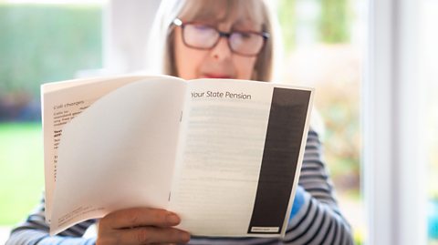 A retired senior woman in her 70s reads information about state pension.