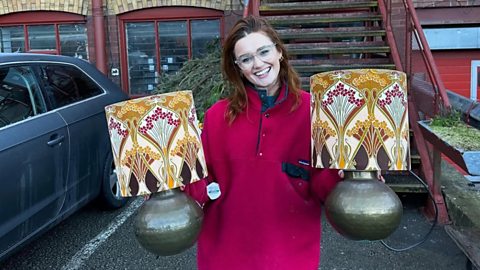 Jes in a carpark holding two vintage lamps.