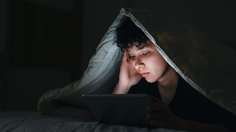 Young person in bed on a device