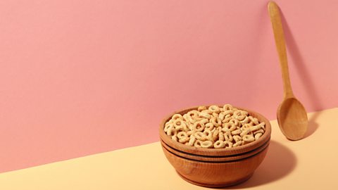 Bowl of hooped cereal in a wooden bowl with a wooden spoon next to it