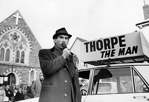 Getty Images Black-and-white archive image of Jeremy Thorpe campaigning with microphone in hand with church in background (Credit: Getty Images)