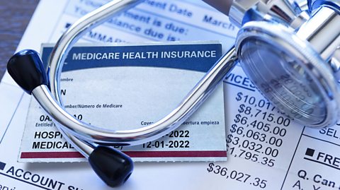 A Medicare insurance card and a stethoscope rest on top of a hospital medical invoice.