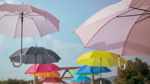 Multicoloured umbrellas are hanging in the air, with bright blue skies in the background