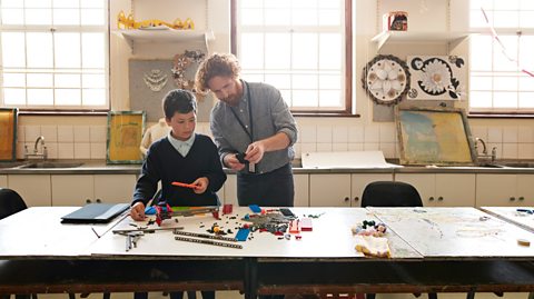 A person and child are solving puzzles in a classroom.