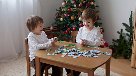 A couple of young boys playing with puzzle pieces.
