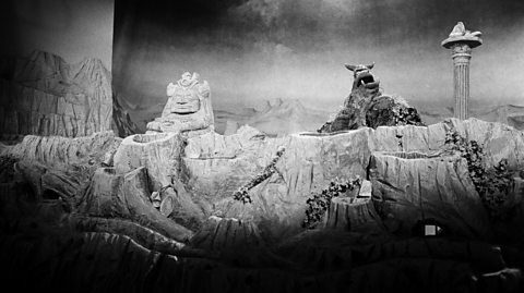 A black and white photo of a The Land of Gorch skit from Saturday Night Live. A large, disgusting looking Muppet is seen overlooking rocky terrain