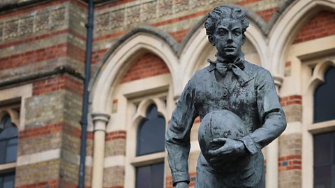 A statue of William Webb Ellis holding a rugby ball