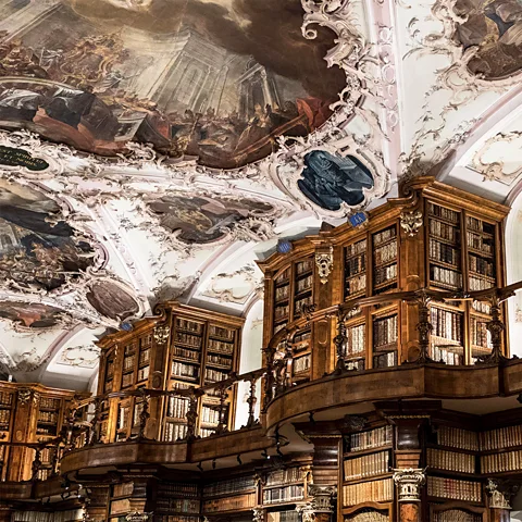 Alamy The fantastical décor includes ornate wooden bookcases and a painted Baroque ceiling (Credit: Alamy)