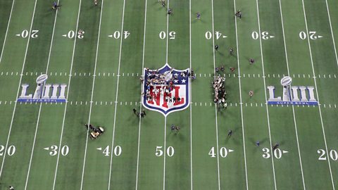 A top down view of an American Football pitch showing the 10 yard markings and the NFL logo
