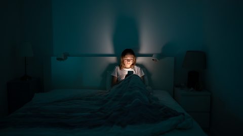 mother scrolls alone in bed