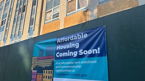 Affordable rent-stabilised housing sign on hospital building being renovated.