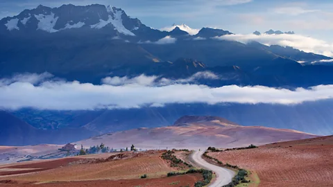 Alamy A curved road heading into the distance with mountains and clouds in the background (Credit: Alamy)