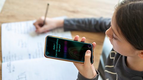 A young person speaks to an AI tool on her phone whilst completing homework