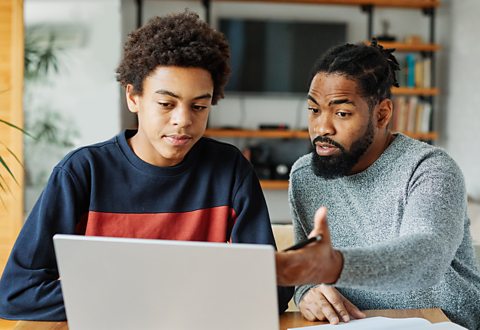 A father and son study together at a laptop