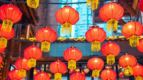 Red lanterns with yellow tassels hang above a street