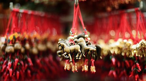 A gold horse souvenir hangs from a red thread in a souvenir shop