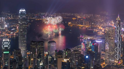 Chinese New Year fireworks in Hong Kong. An aerial view of the city at night, with skyscrapers lit up and a bright firework display in the centre of the water