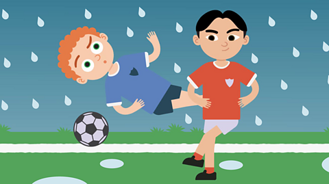 Illustration of two footballers, it is raining and the pitch has puddles. The player on the left is jumping up and looks like they might fall over. Learning about adjectives is useful for pupils studying for the SEAG transfer test