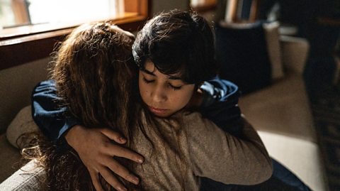 Mother comforts sad son in living room