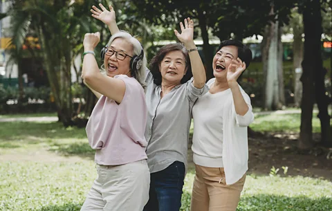 Getty Images Three women singing and waving their hands in the air (Credit: Getty Images)