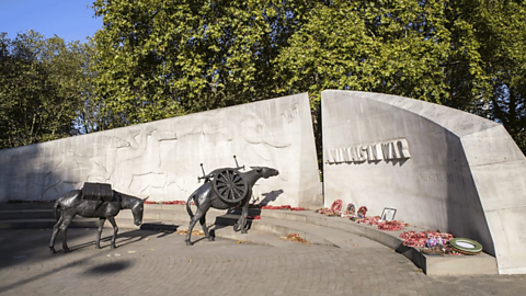 A marble memorial wall with two horse statues