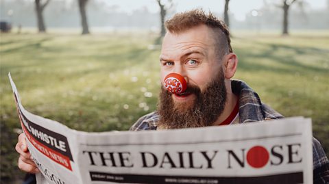 Joe Marler wearing a red nose whilst reading 'The Daily Nose' newspaper