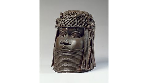 Image of Benin brass showing the head of an Oba. They are wearing a bead crown made from coral.