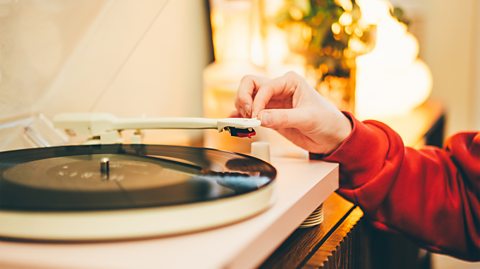 Close-up of a woman listening to music with a vinyl record player at home.