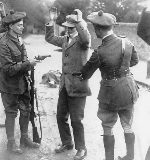 A suspected member of the Irish nationalist party Sinn Fein is searched at gunpoint by 'Black and Tans', 1920