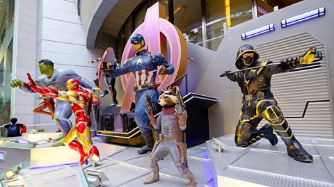 A stage full of mannequins of Marvel superheroes in various poses. From left to right, the green Hulk with dark hair and a grey shirt, Iron Man in a red and gold iron suit, Captain America with a navy suit, white stars and red and white stripes with a circular shield, Rocket Raccoon with a grey and red suit and Hawkeye with a black hood and yellow stripes 