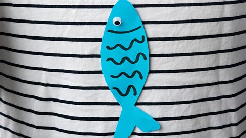 A paper fish stuck to a black-and-white striped top
