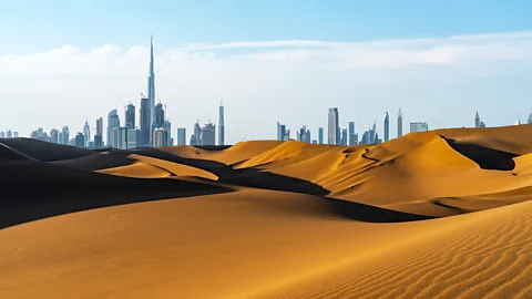 Getty Images The Dubai skyline behind undulating sand dunes (Credit: Getty Images)