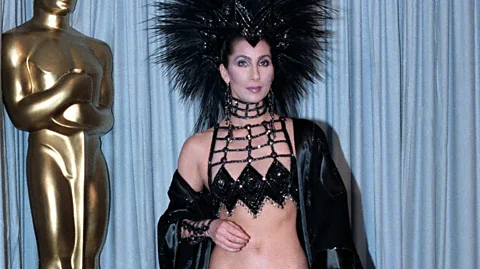 Getty Images Cher in a revealing black top and jacket and black headress at the 1986 Oscars (Credit: Getty Images)