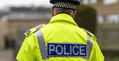 Image of a police officer, he is wearing a hi-vis jacket with word POLICE in capital letters on the back.