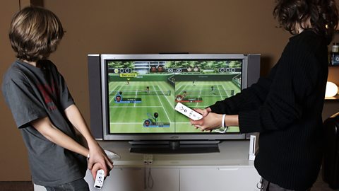 Two children playing Wii Sports in tennis mode in front of their tv. Both are holding white Wii Remote controllers