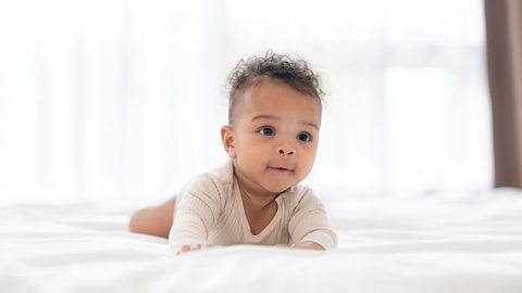 A baby crawling on a white duvet