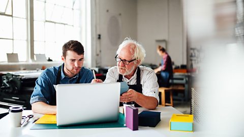 A younger man working alongside an older man in an art and design workshop