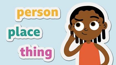 A girl points at her head while studying nouns for the SEAG transfer test. Beside her are the words person, place and thing.