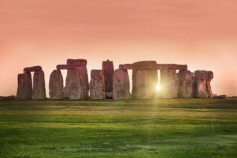 Stonehenge stone structure with sun setting and shining through the middle of stones