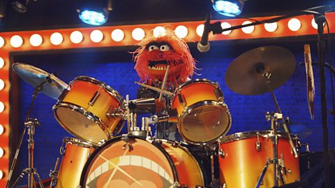 The Muppet Animal sat behind a drum set