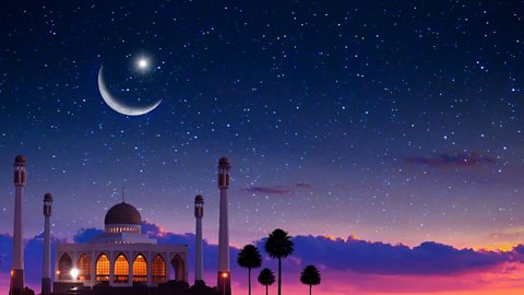 A crescent moon in a starry sky over a mosque 
