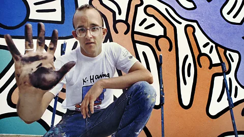 Getty Images Keith Haring crouching in front of one of his artworks (Credit: Getty Images)