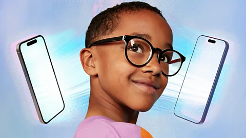 Serenity Strull/ Getty Images A child looks up with two bright phone screens on either side of their face (Credit: Serenity Strull/ Getty Images)