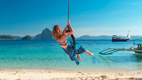 Alamy A woman swings on a vine into the water at El Nido Beach in the Philippines (Credit: Alamy)