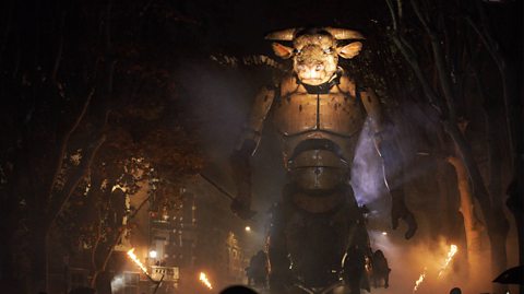 A large machine of a minotaur, a half man half bull mythical creature, walks through the streets of Toulouse, France, as part of an art exhibition. It is large and brass like, with a stern look and big horns