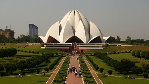 A shot of New Delhi's Lotus Temple behind gardens