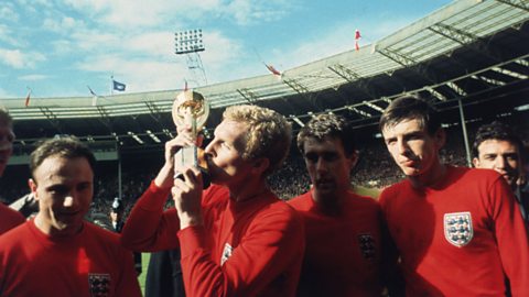 Bobby Moore, wearing the famous red England shirt, kisses the World Cup trophy at Wembley stadium.